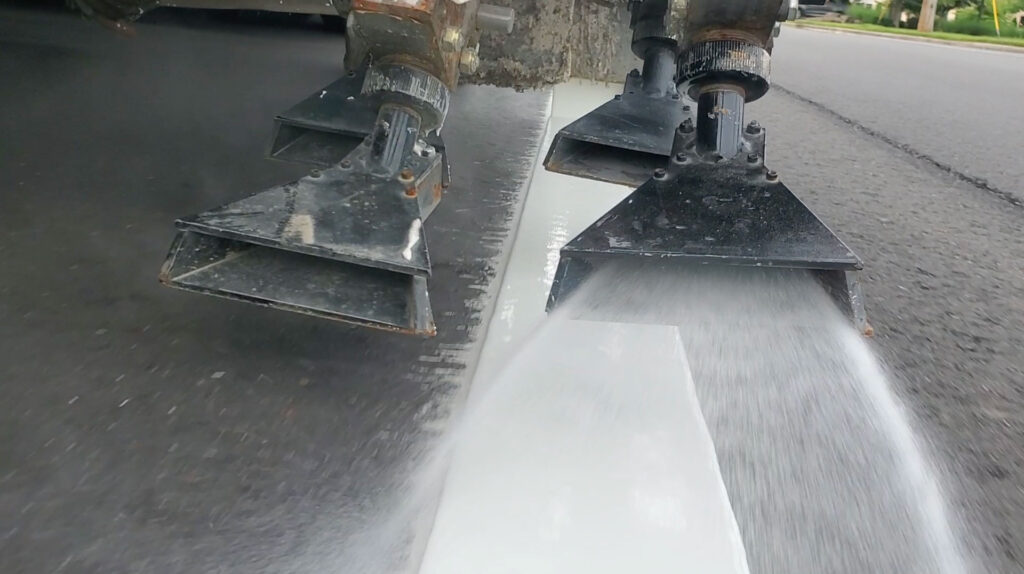 Road construction bead gun showing reflective beads being applied to road striping